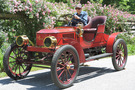 Tom Marshall riding the 1908 Stanley Model H-5, a bright red car with red wheel spokes