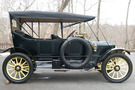 The 1913 Stanley Model 76 has a dark green body and a lemon yellow undercarriage and wheel spokes. The top of the car is up, covering the passenger seats.
