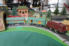 Picture of 3 Lionel electric train cars on a track. One car is maroon and the other two are green
