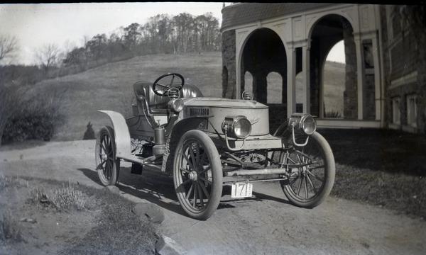The 1907 Stanley Model K Semi-Racer sits in front of the arch of the Auburn Heights mansion. The photograph is in black and white