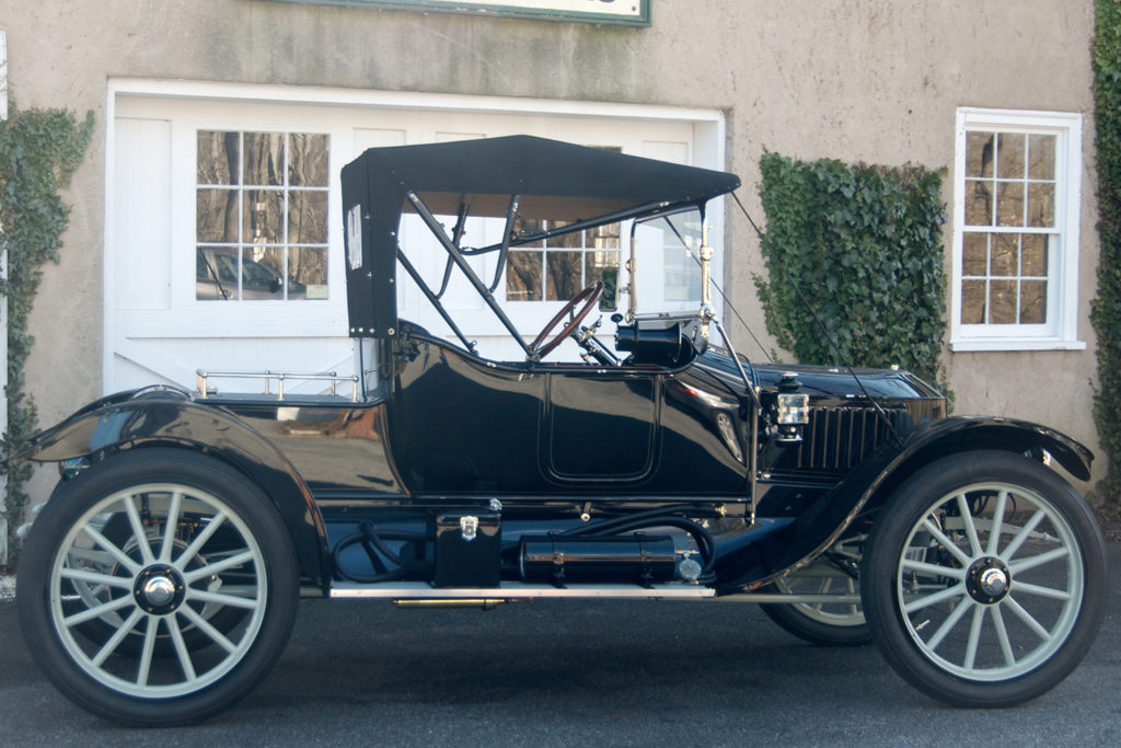 The 1913 Stanley Roadster Model 78 is a glossy back car, with blue wheels, a space on the back for trunks, and a black top