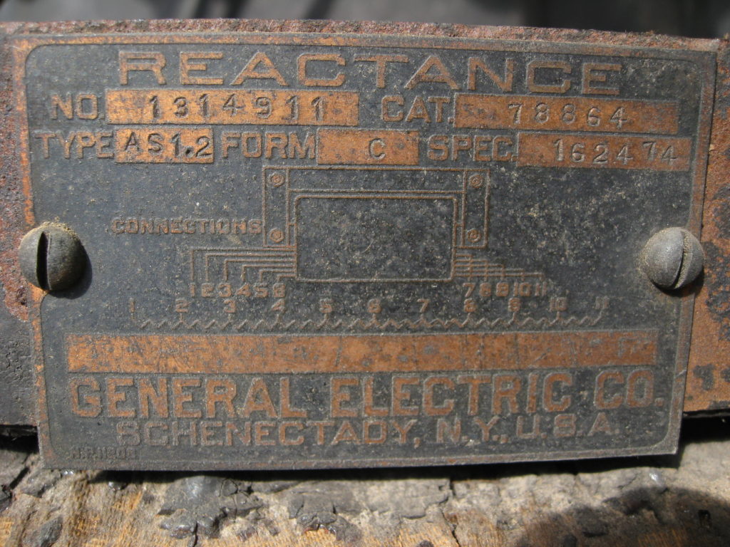 A metal label that has electrical diagrams on it, in large text it reads "General Electric Co. Schenectady, N.Y., U.S.A.